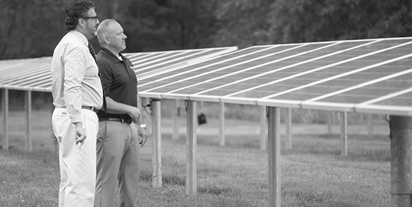 BankFive Commercial Lender Paul Medeiros and a BankFive business loan customer standing alongside solar panels at a solar farm
