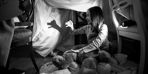 girl making finger puppets with flashlight during power outage
