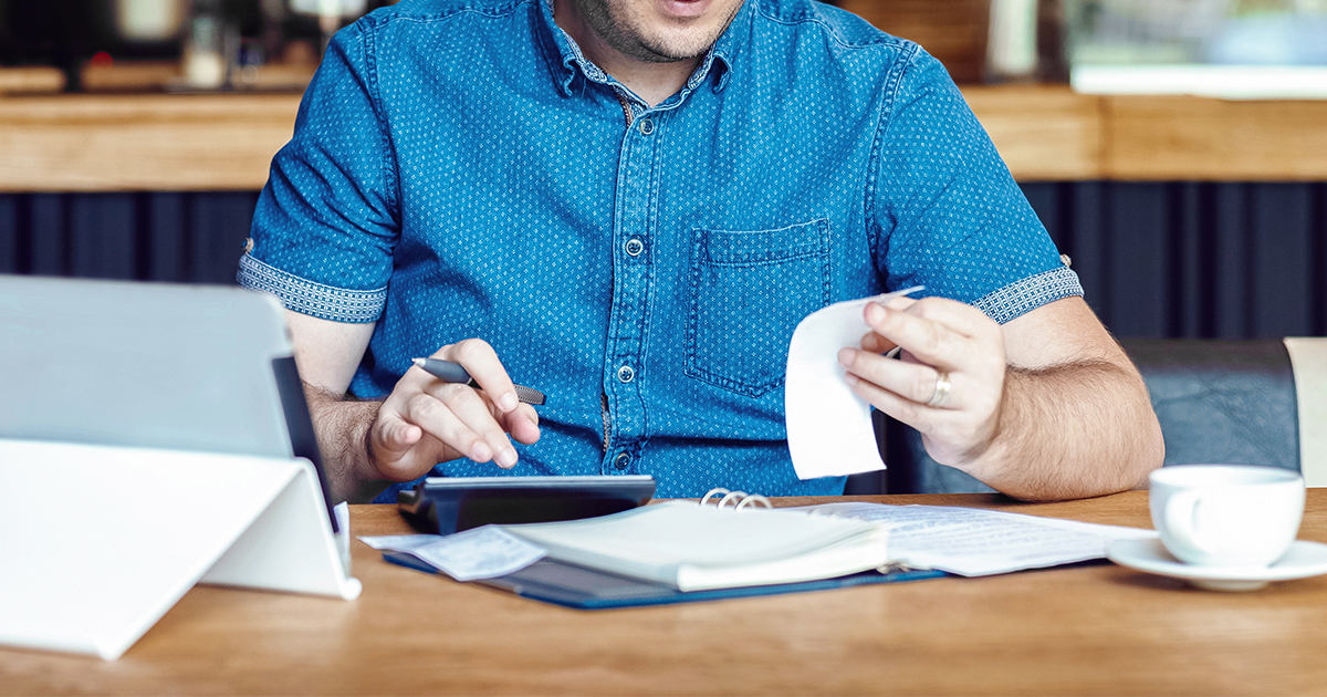 man reviewing business receipts with calculator