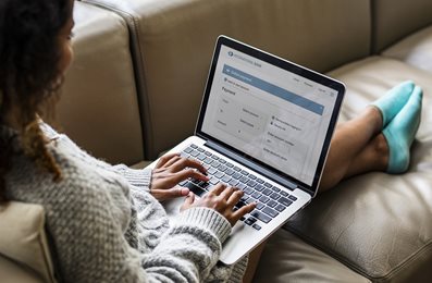 woman sitting on couch using online banking on her laptop