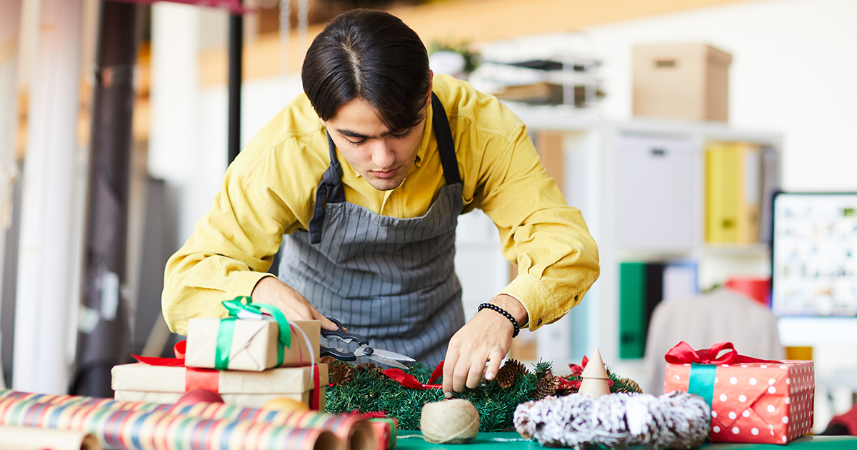 person putting decor on a wreath