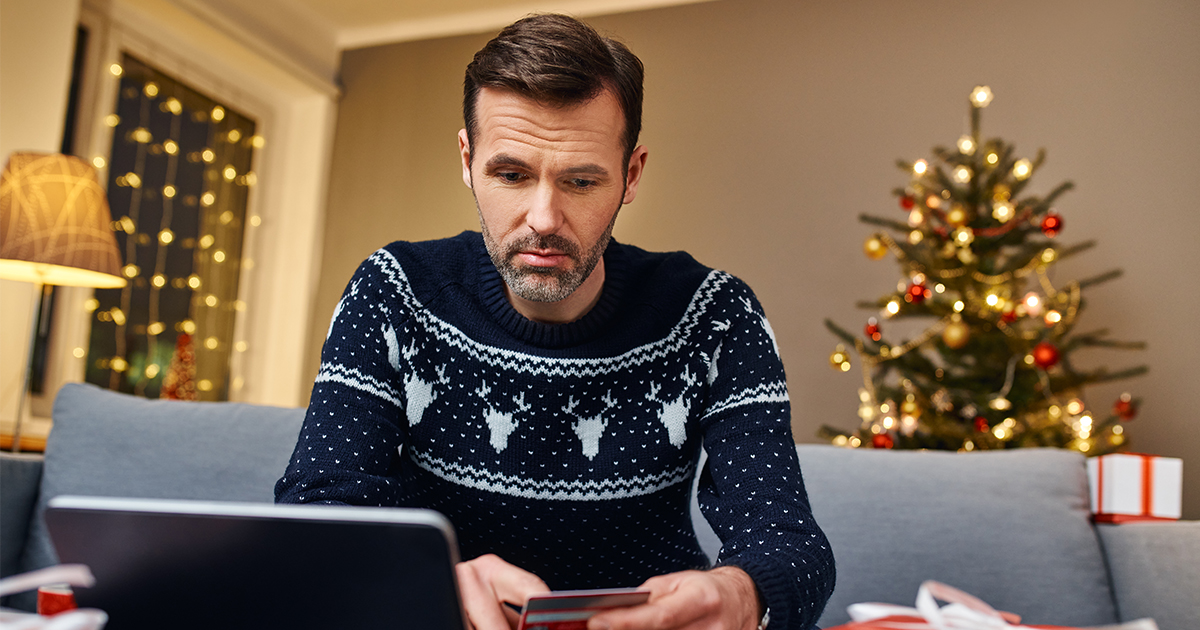 person looking at bank card with holiday sweater