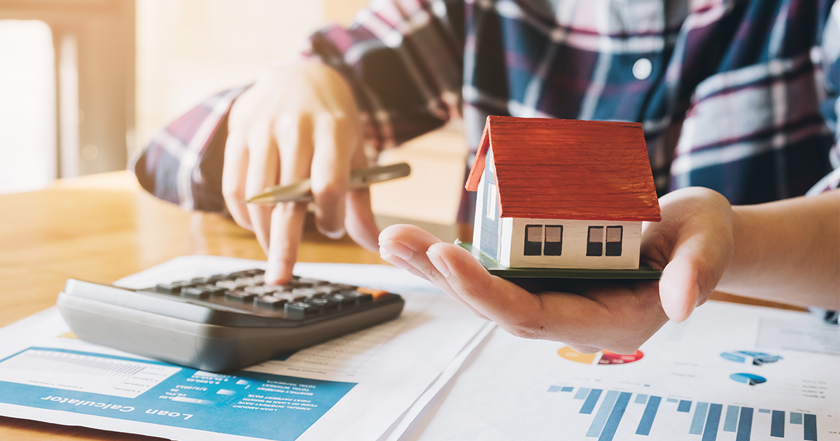 person on calculator with toy house figure