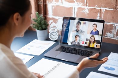 woman video conferencing with colleagues at desk
