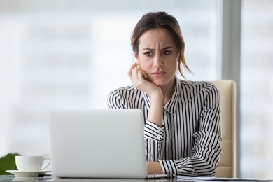 Woman looking at her laptop confused