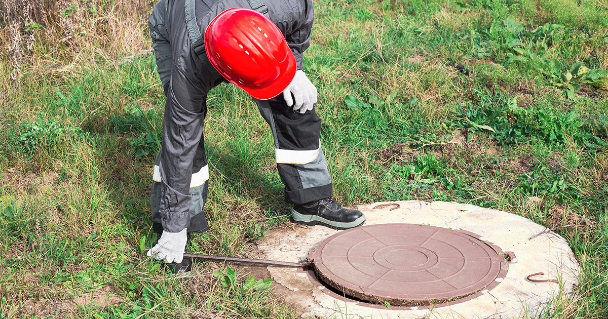 man opening septic tank in the ground