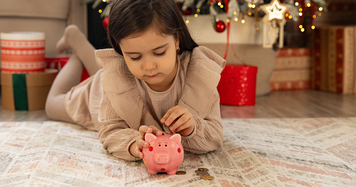 child putting coin in piggy bank