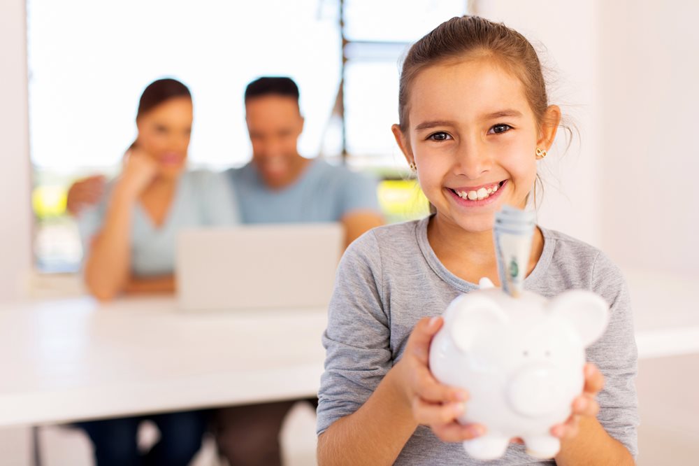 kid smiling with piggy bank