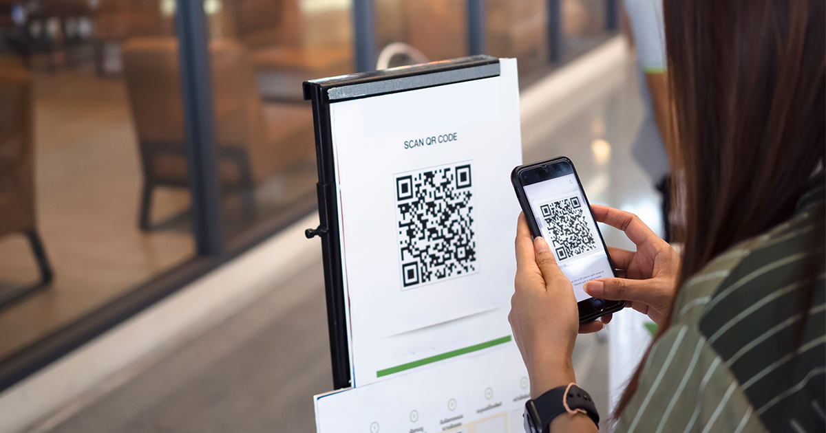 person scanning QR code on restaurant sign